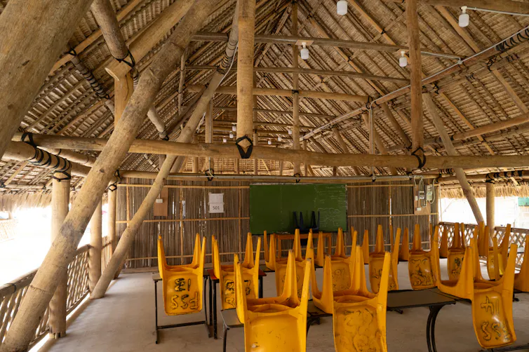 Interior of a classroom with exposed timber beams, a high thatched roof.