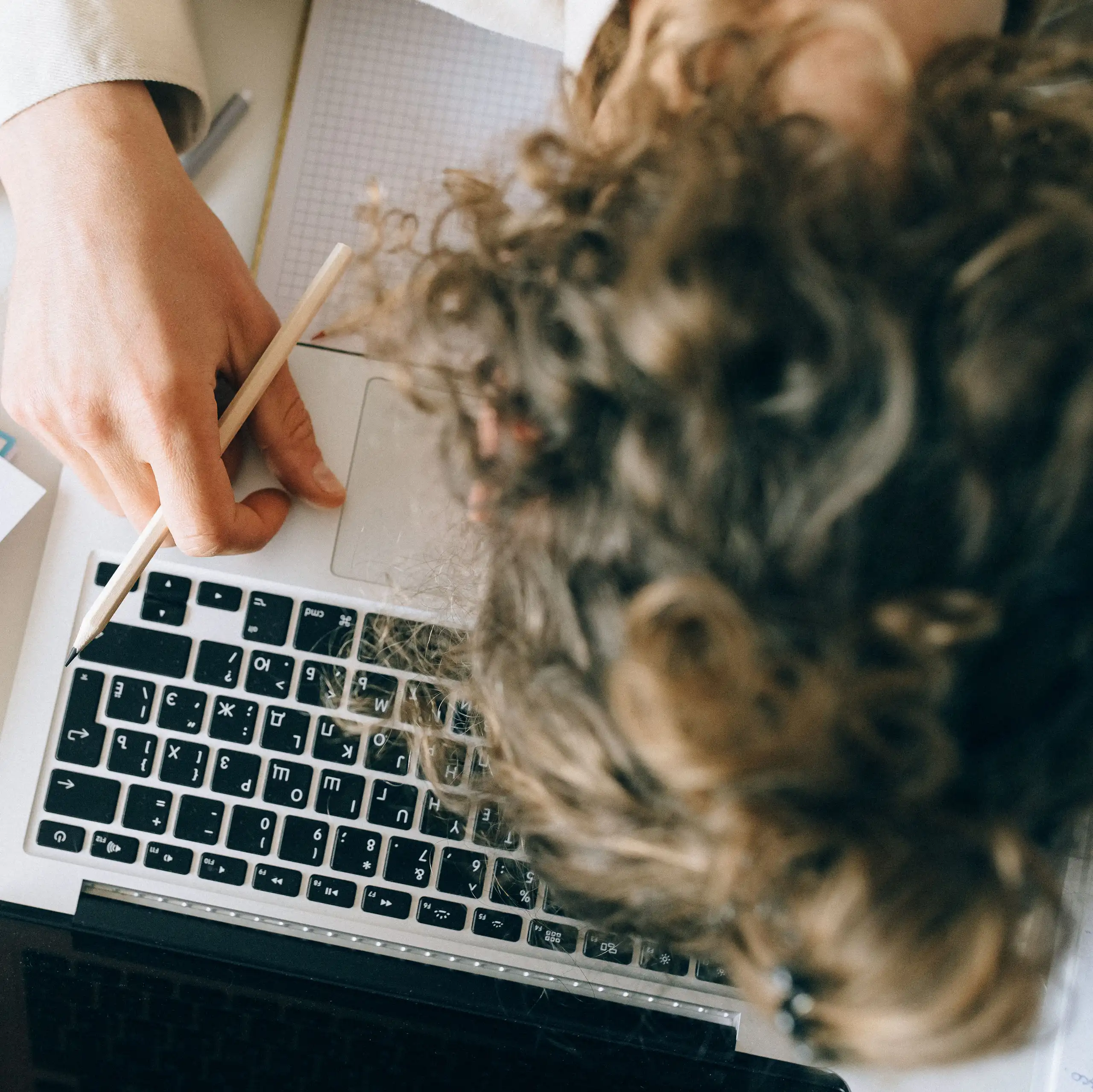 A woman rests her head on top of a laptop and books.