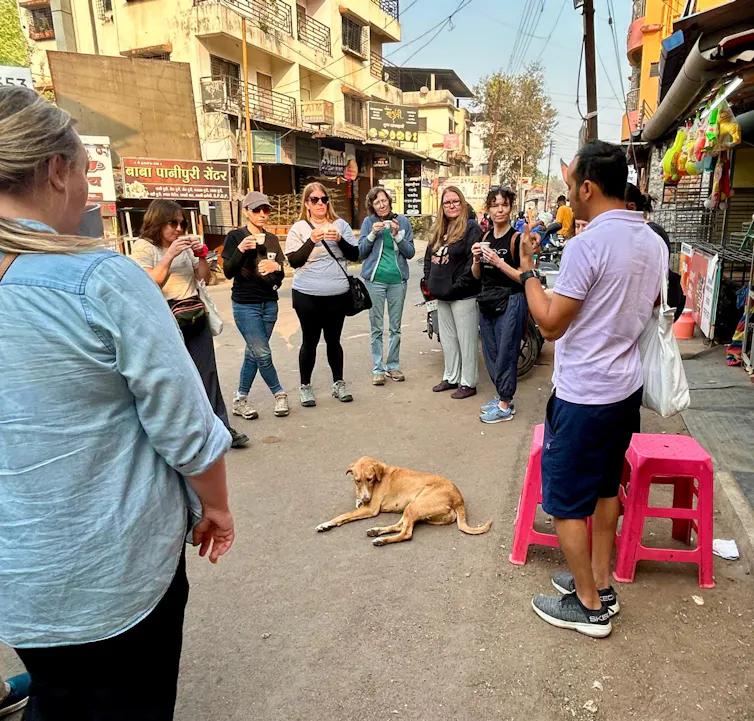 people standing in a circle on indian street looking at a street dog.