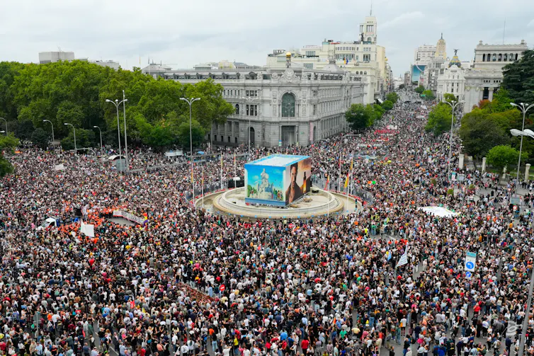 A large, European public square overflowing with protest crowds