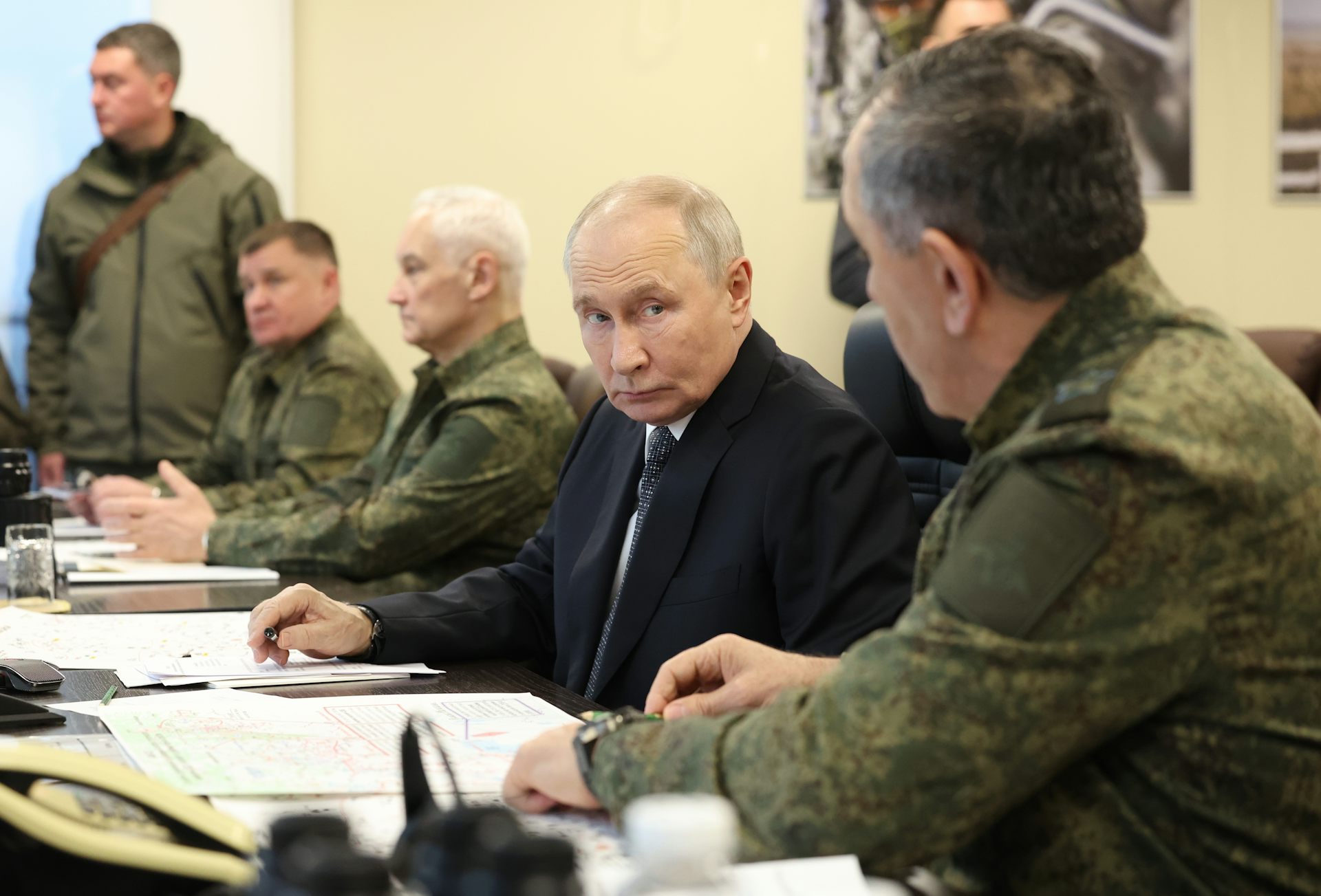 Vladimir Putin sat at a desk alongside Russian military officials.