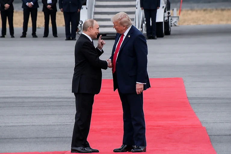 US president Donald Trump and Russian president Vladimir Putin stand togather on a red carpet in Alaska.