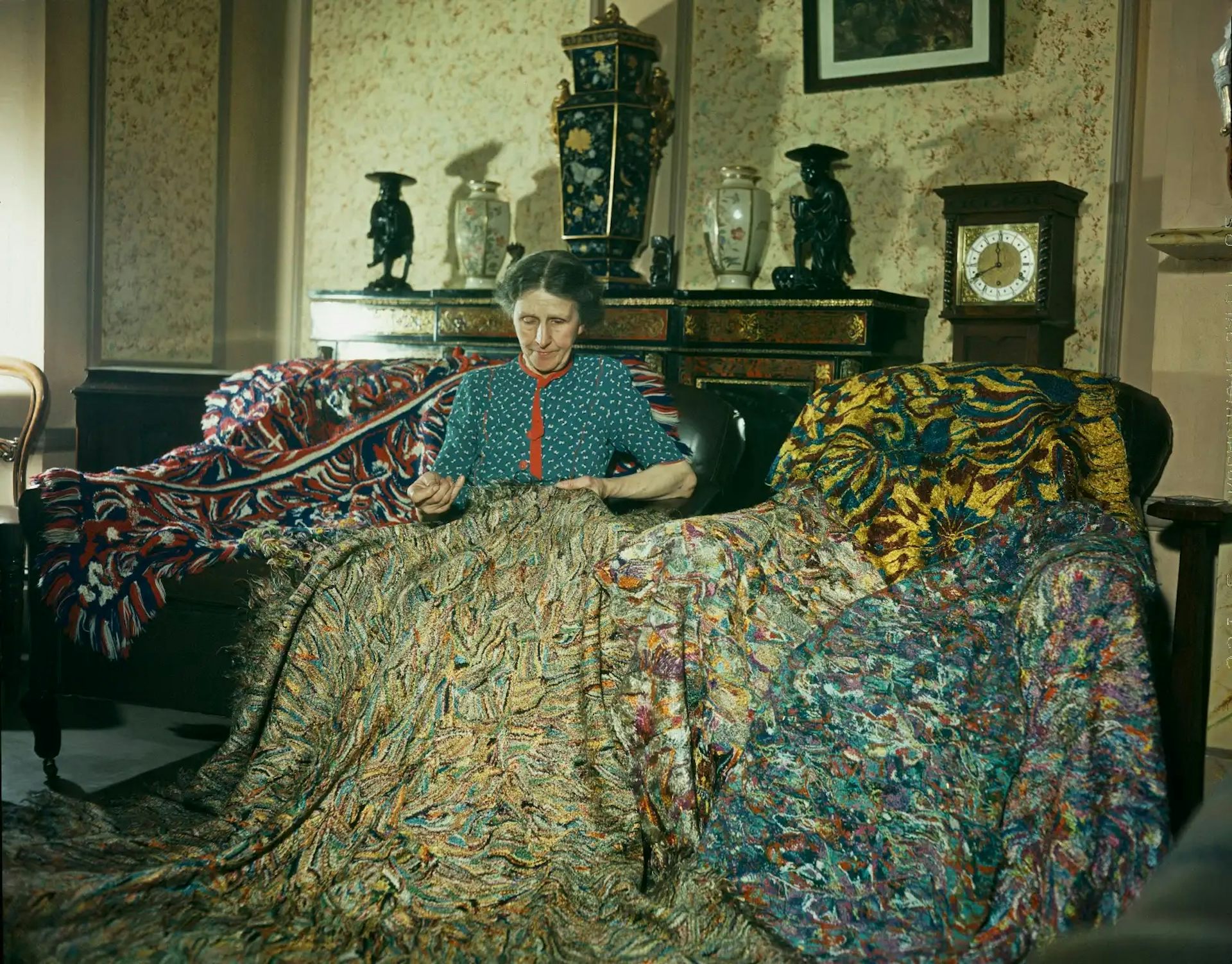 English artist Madge Gill making a rug by inserting left over strands of silk into a canvas backing.