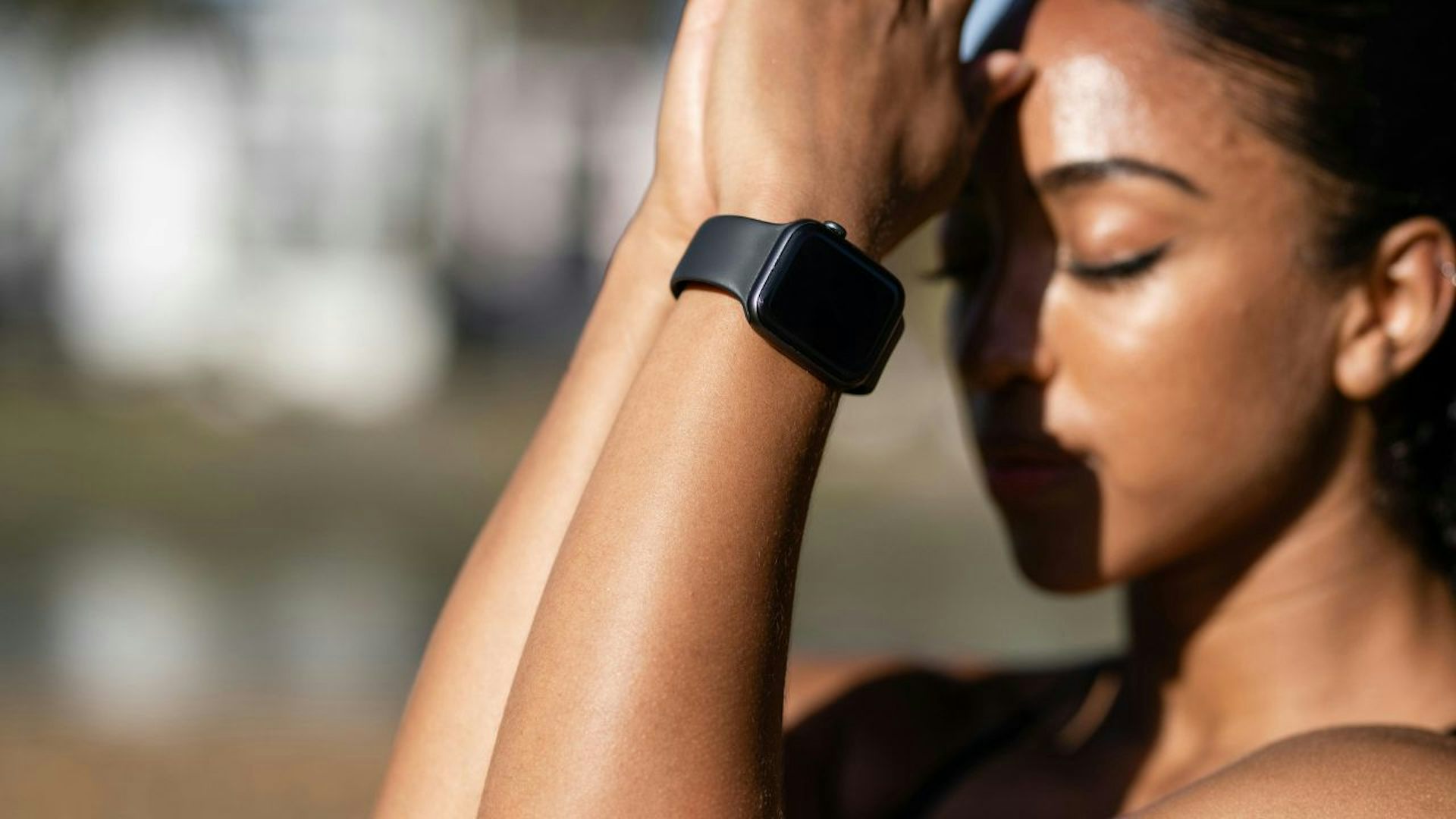 Woman wearing a black smartwatch with her eyes closed, appearing to meditate.
