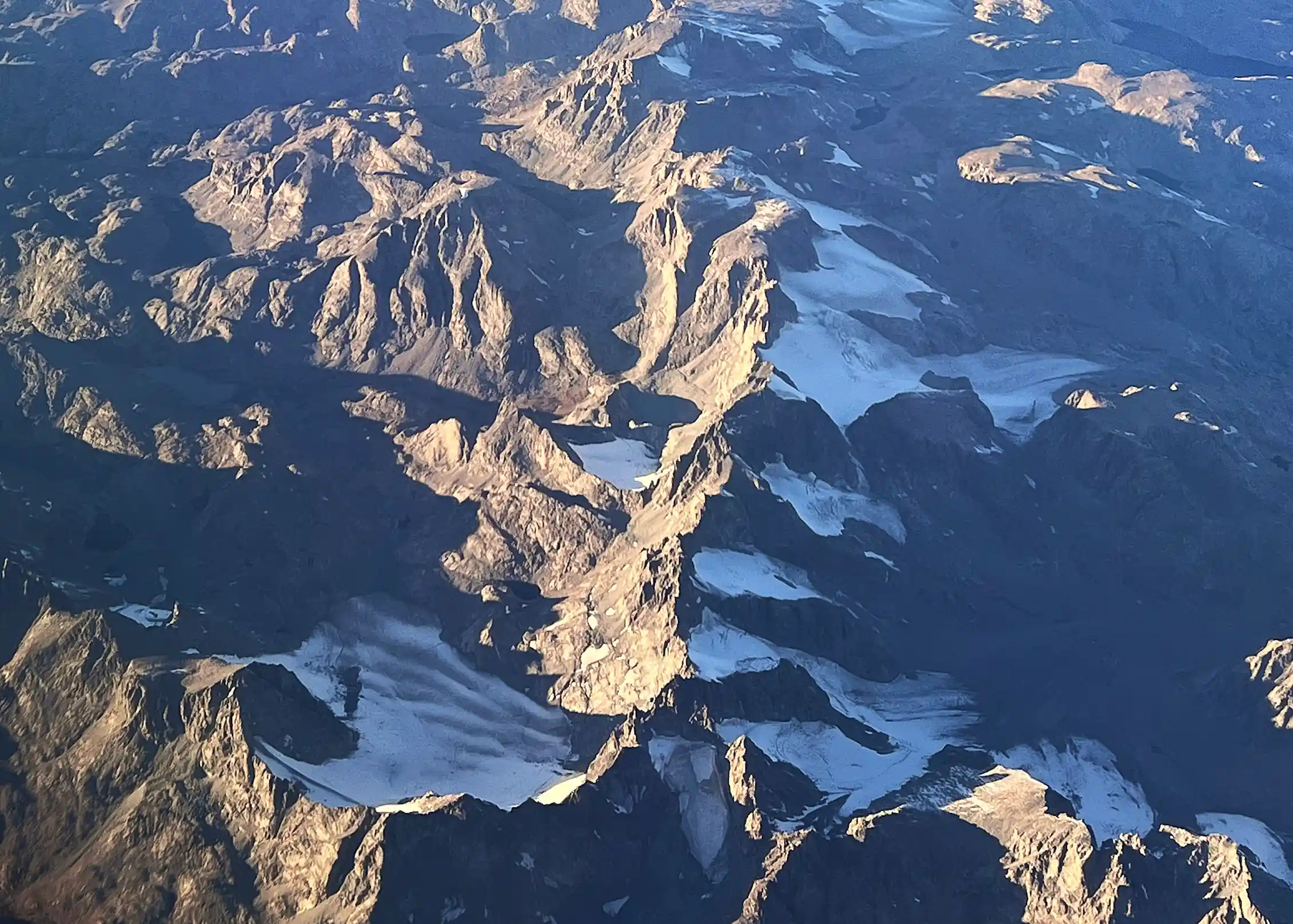 Several glaciers nestled in shaded areas of high mountains.