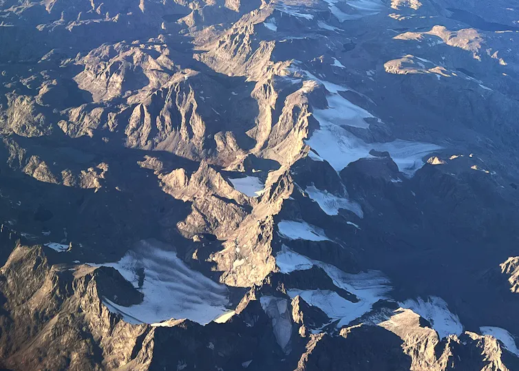Several glaciers nestled in shaded areas of high mountains.