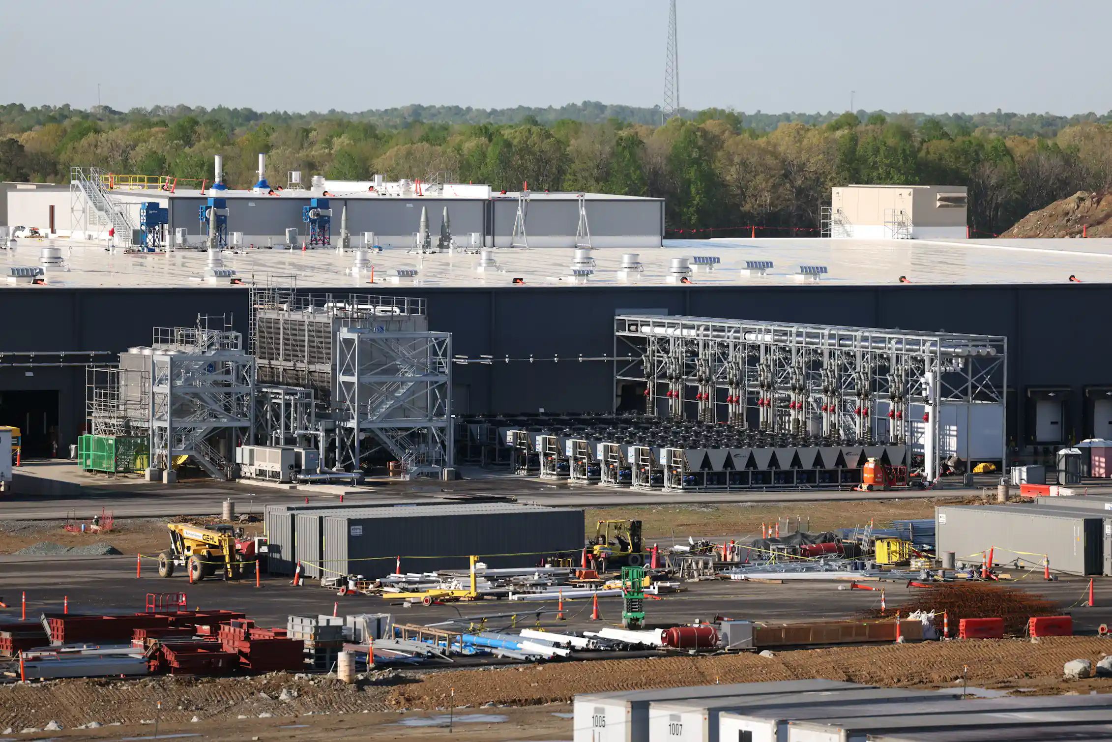 A large building is under construction, with many trucks and other pieces of equipment outside.