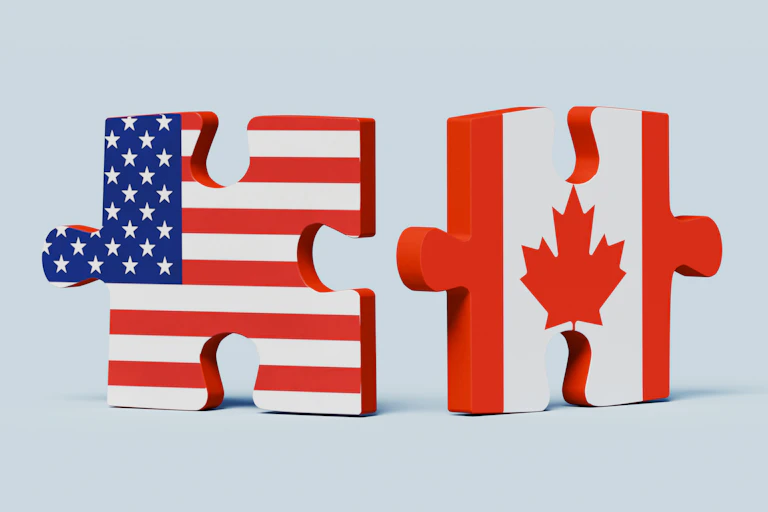 Two puzzle pieces, one with a U.S. flag and the other with a Canadian flag, stand next to each other, close but not quite connected.