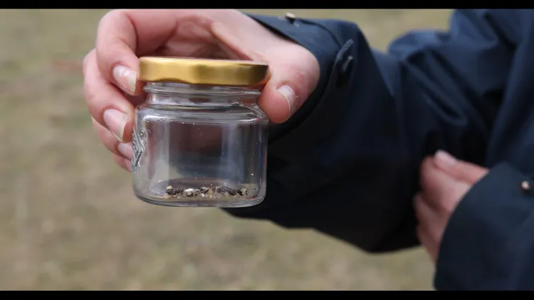 A woman holds a jar of tiny droppings.