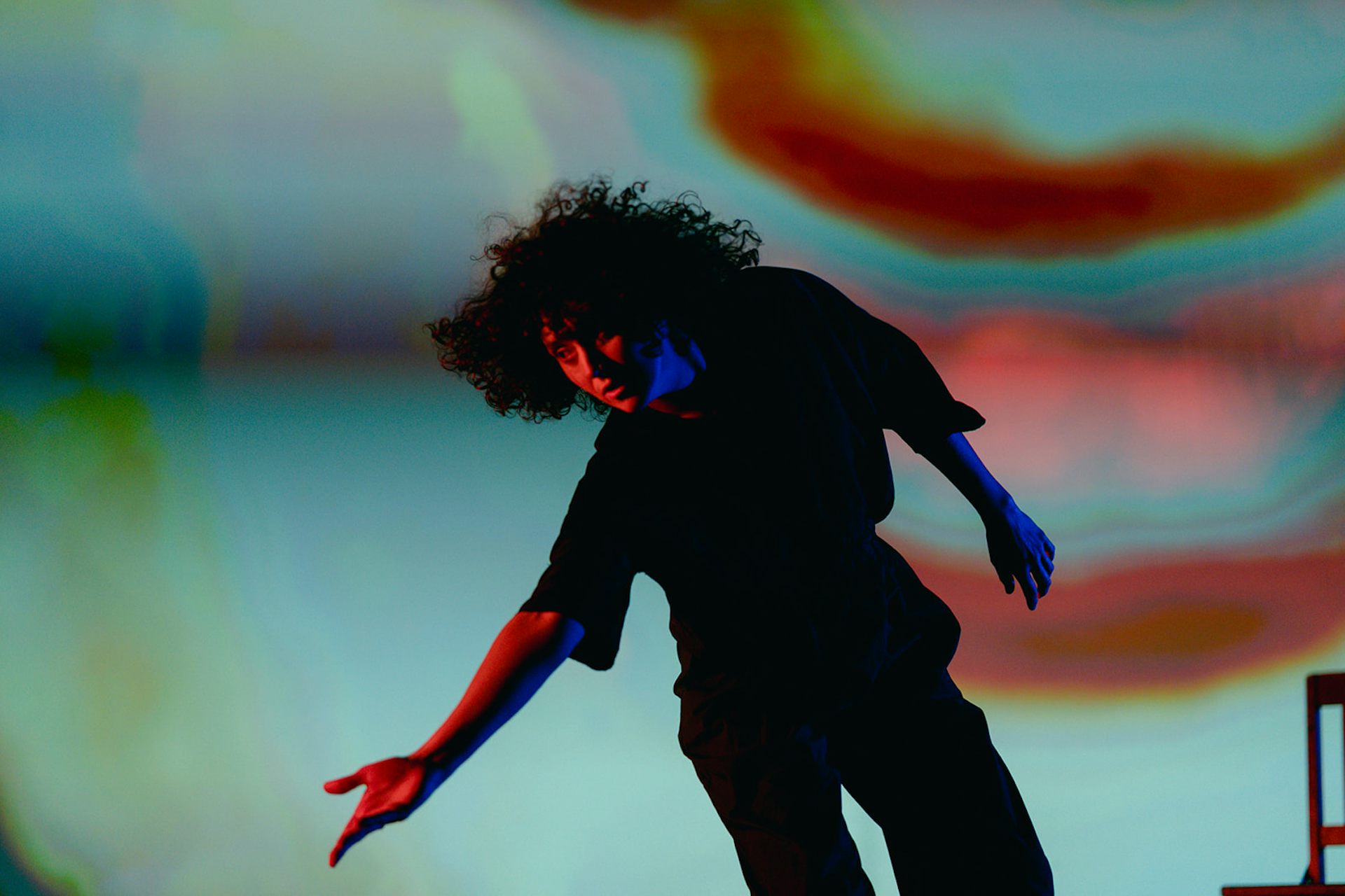 A performer dancing on stage, with abstract projections behind them.