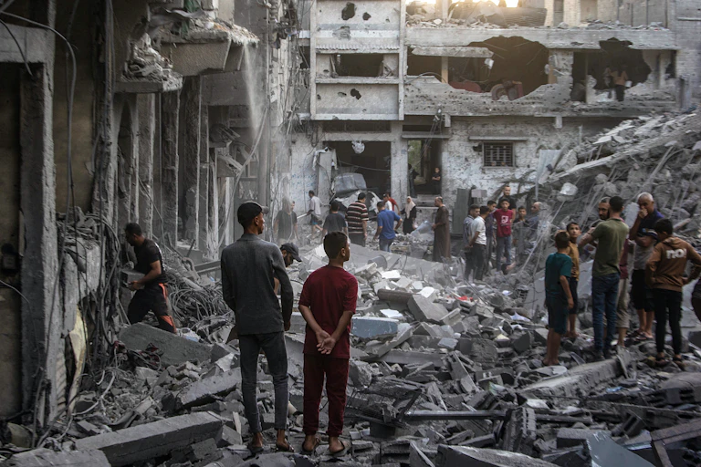 "Palestinians stand in the ruins of the Al-Sabra neighbourhood of Gaza City, 09 October 2026.