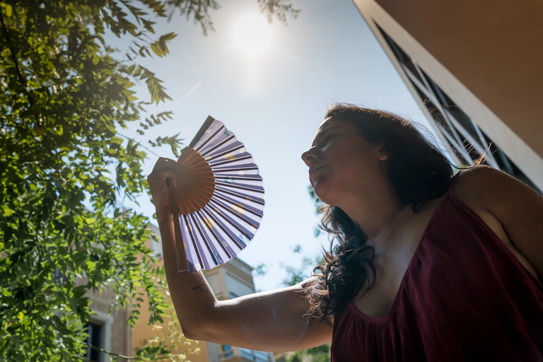 A woman fanning herself on a hot day.