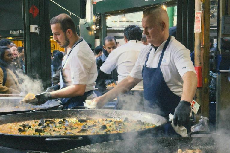Des hommes cuisinent la paella.
