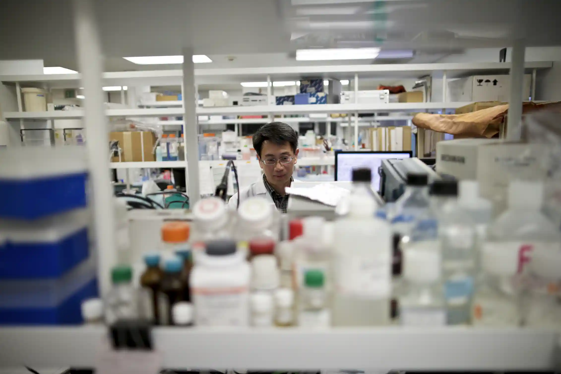 Scientist seen between stacks of lab equipment and materials