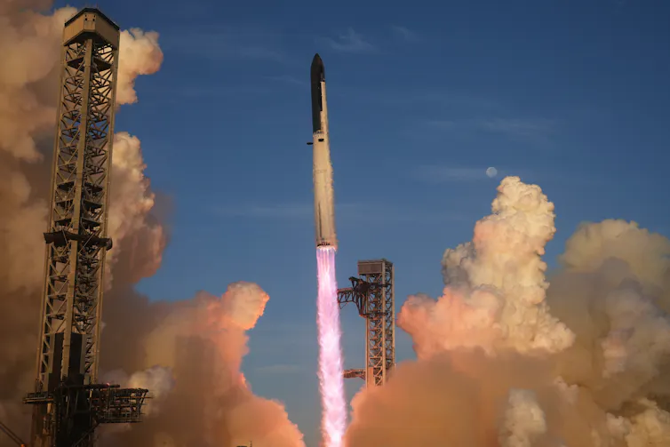 A rocket launching with a plume of smoke and flame lifting it off the ground, and smoke visible in the background.