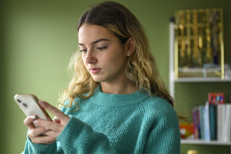 Teen girl looks at her phone.