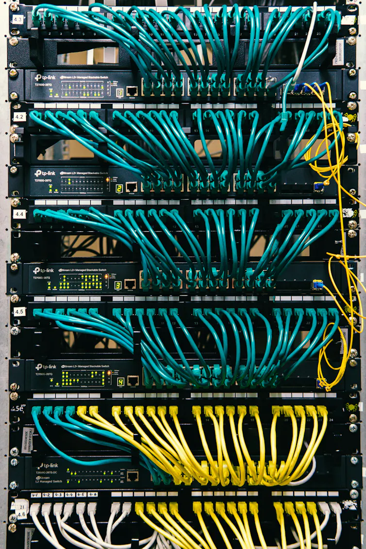 A stack of electronic equipment with many looping blue and yellow cables