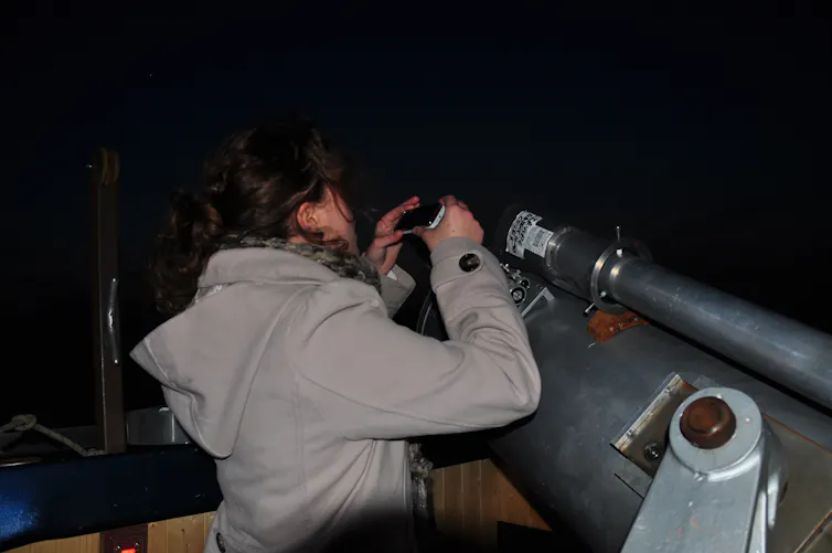 Woman looking into telescope.