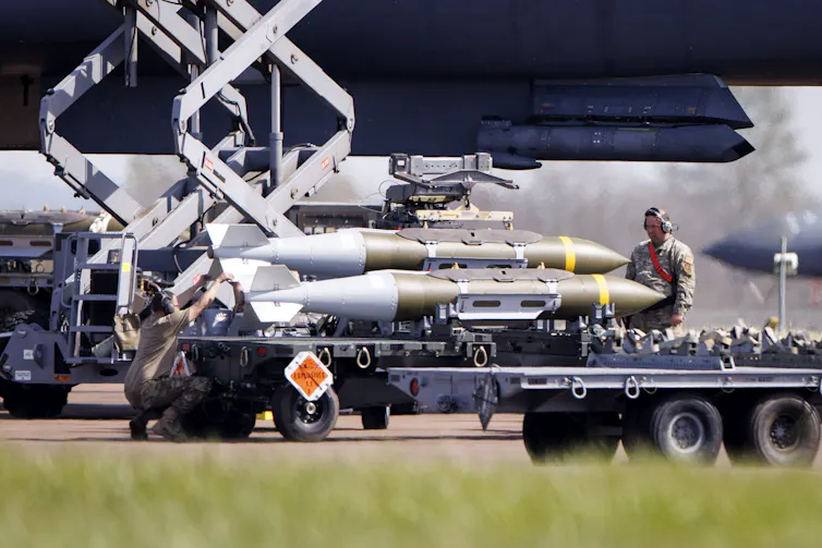 US Air Force military personnel standing next to munitions on the tarmac at RAF Fairford.