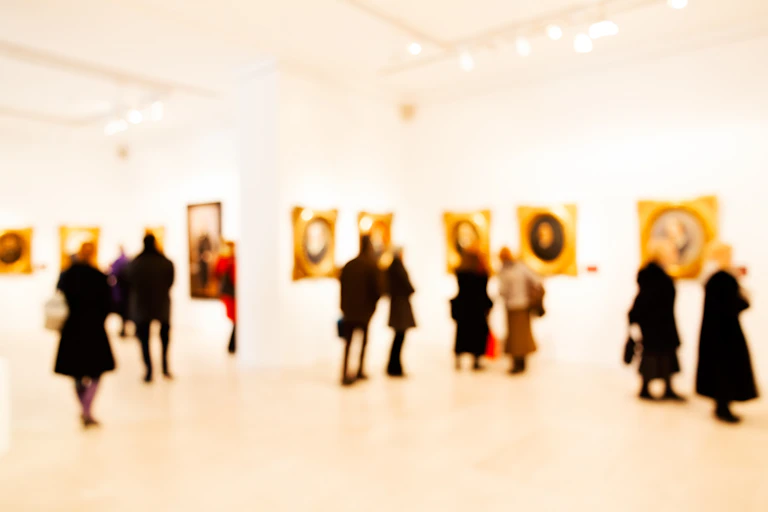A group of people, out of focus, looking at art in a gallery