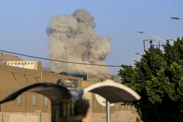 A plume of smoke rises above a building.