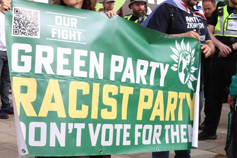 Protestors outside the Green party conference with a banner saying the party is racist