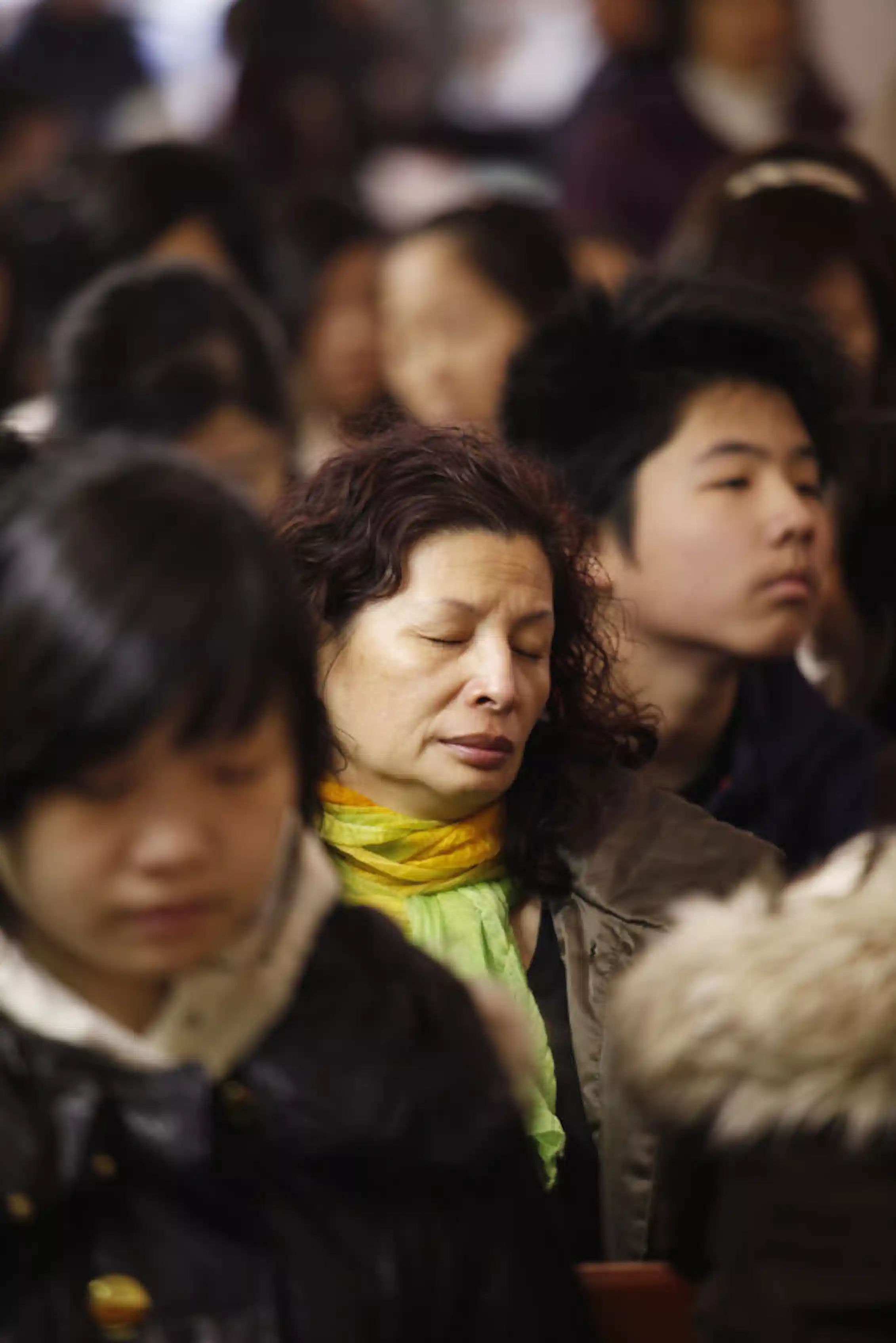 About half a dozen people, some closing their eyes in prayer, sit in church pews.