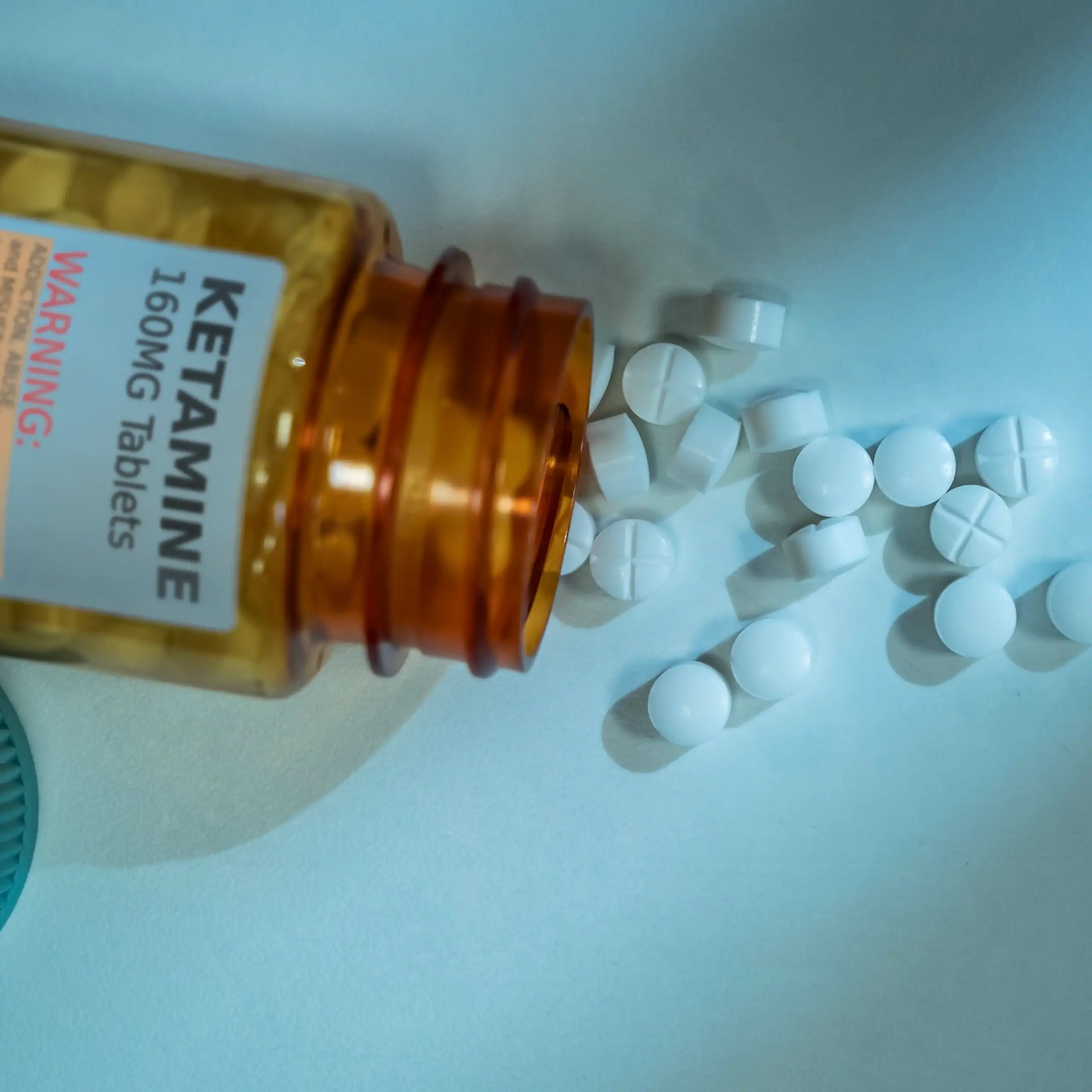 Pill bottle that says "Ketamine 160 Mg Tablets" lying open with pills spilling out.