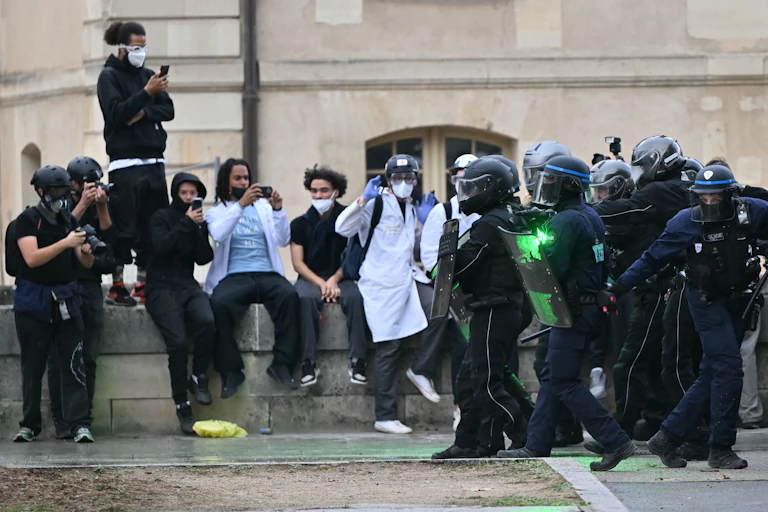 Des manifestants prennent des photos avec leurs téléphones portables de policiers anti-émeutes lors d'une manifestation de lycéens à Paris, le 13 octobre 2026, dans le cadre d'une mobilisation nationale des lycéens.