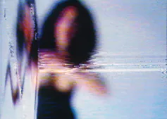 Imagen de una mujer con vestido y melena negros desenfocada.