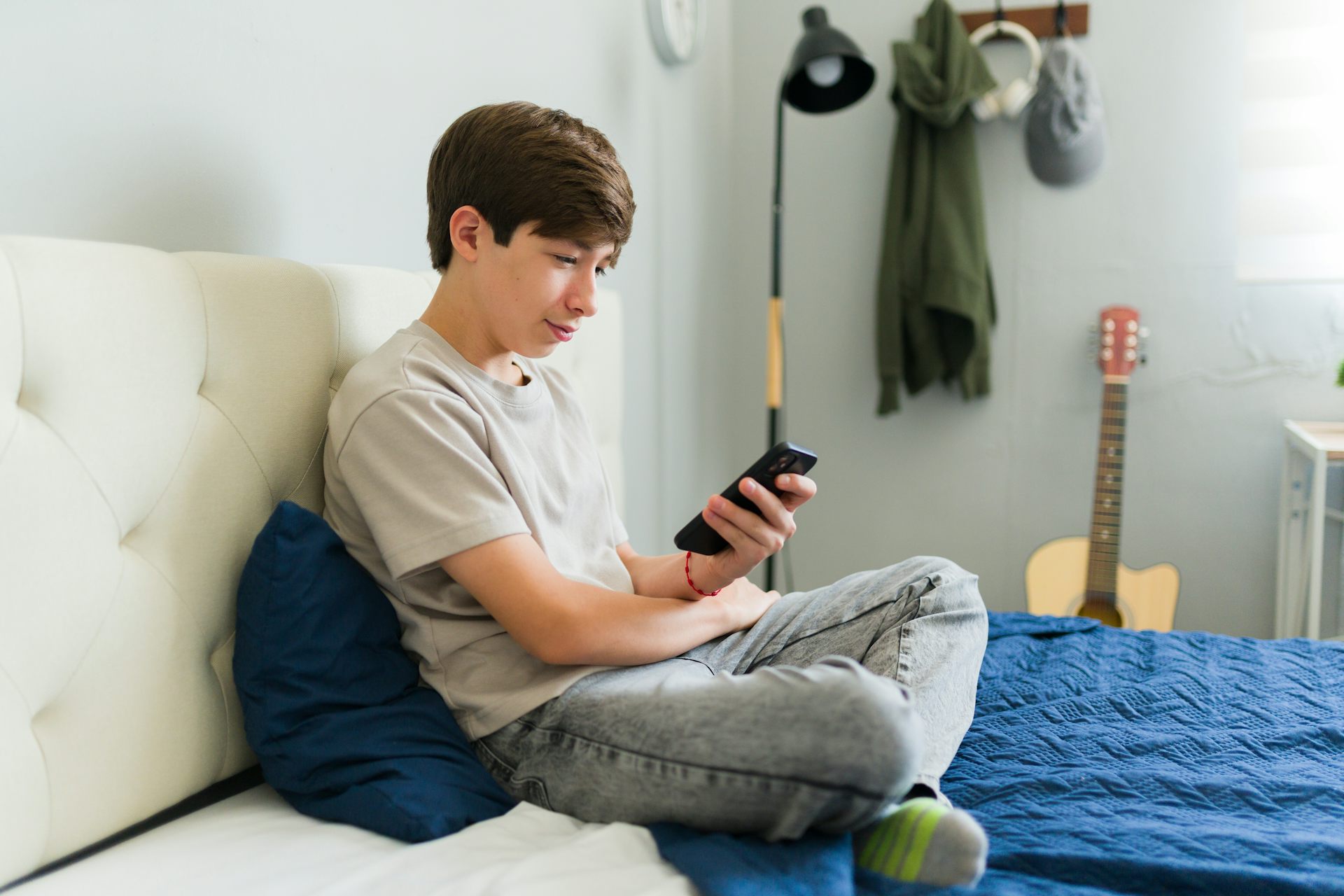 Boy sat on bed looking at phone
