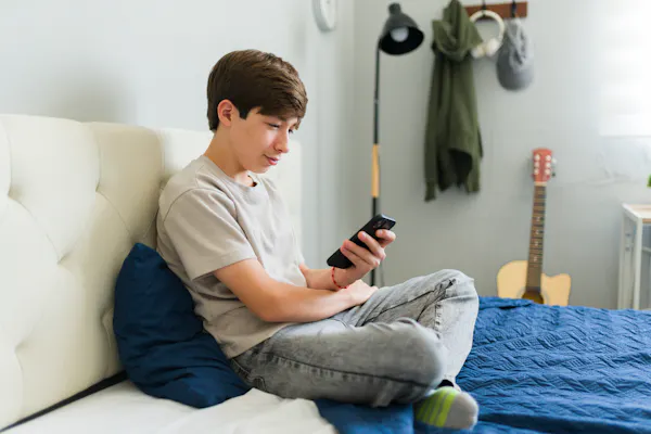 Boy sat on bed looking at phone