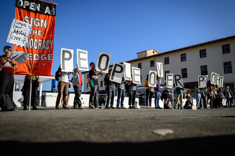 People seen with signs that say 'people over profit.'