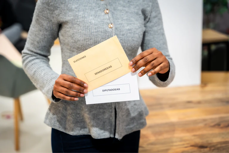 Manos sujetando papaletas de voto