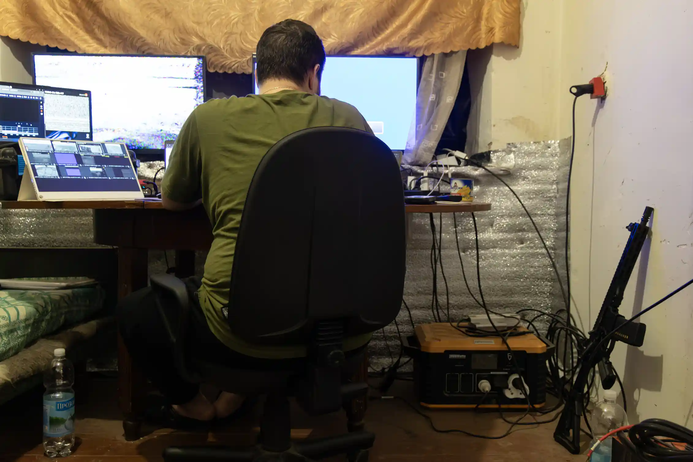 A man sits in front of a bank of computer screens.