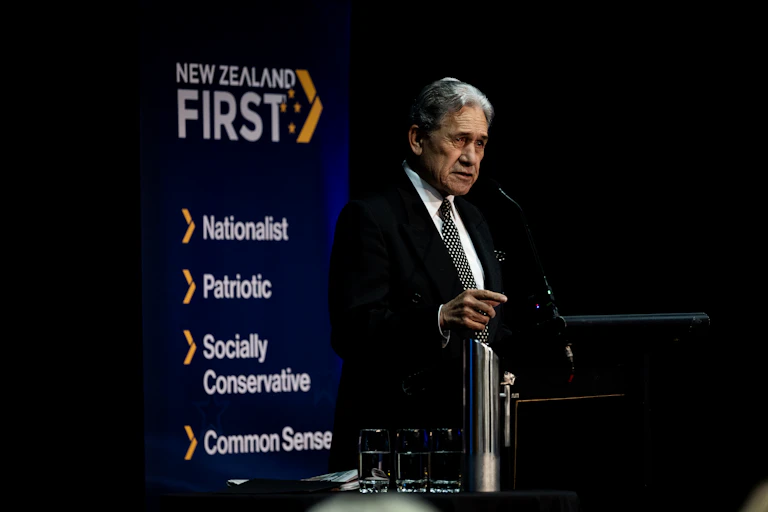 Winston Peters addressing party meeting with NZ First banner in background