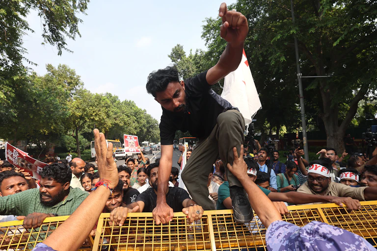 Indian protesters climb over police barricades in New Delhi.