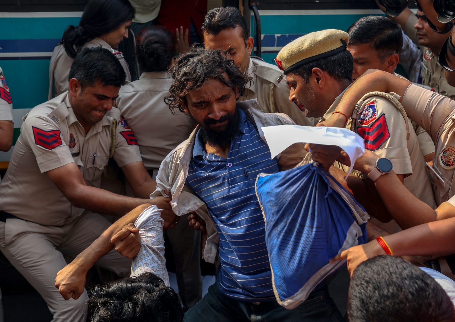 Several Indian police officers detain a protester during a demonstration.