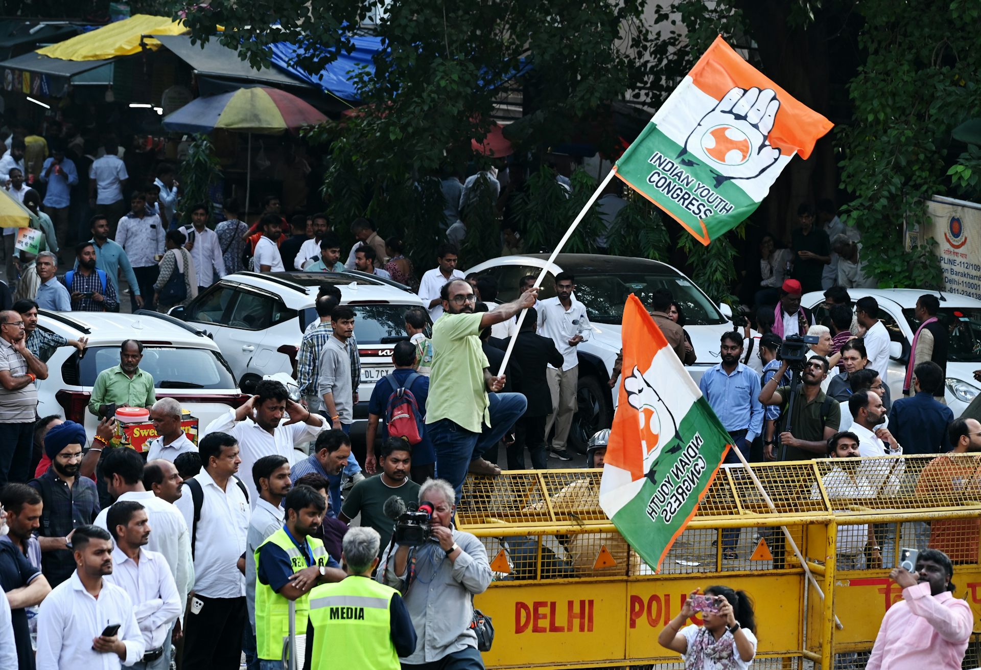 A man waves a Indian flag with the words 'Indian Youth Congress' on it during a protest.