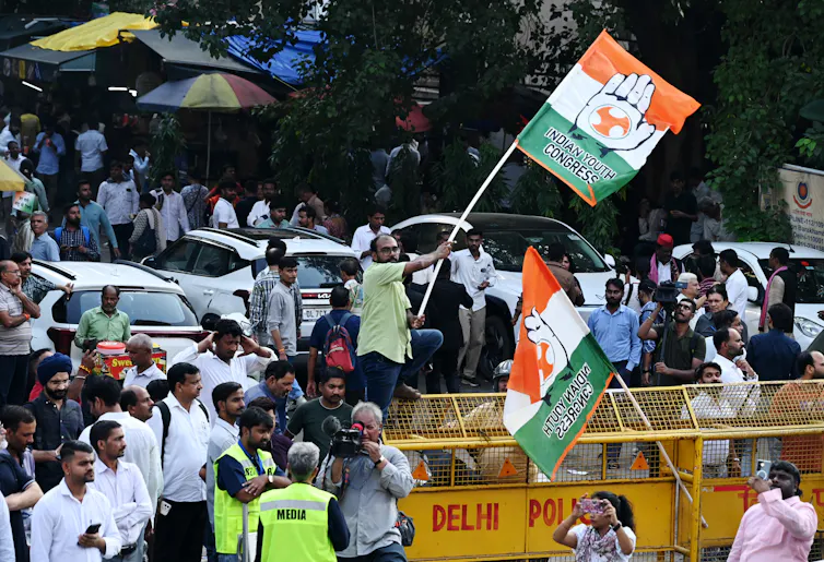 A man waves a Indian flag with the words 'Indian Youth Congress' on it during a protest.