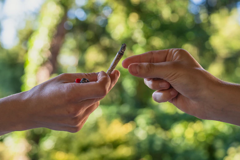 A person passing a cannabis 'joint' to another person.