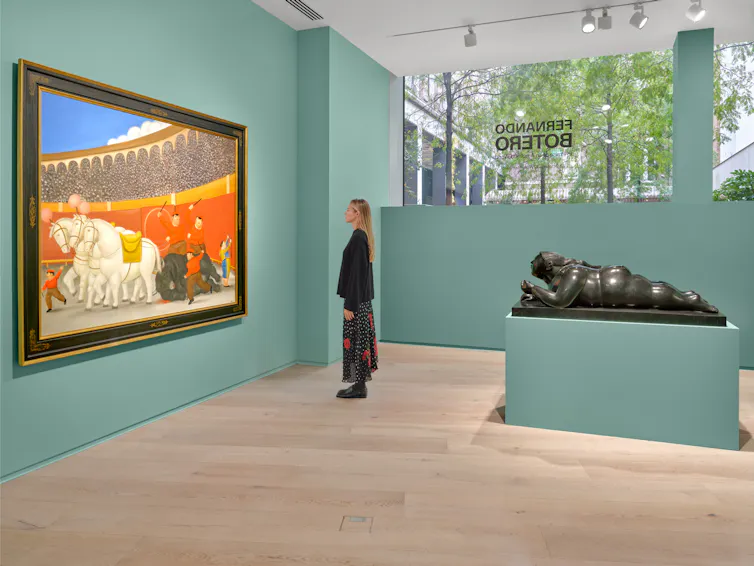 A woman looking at a large painting in the gallery