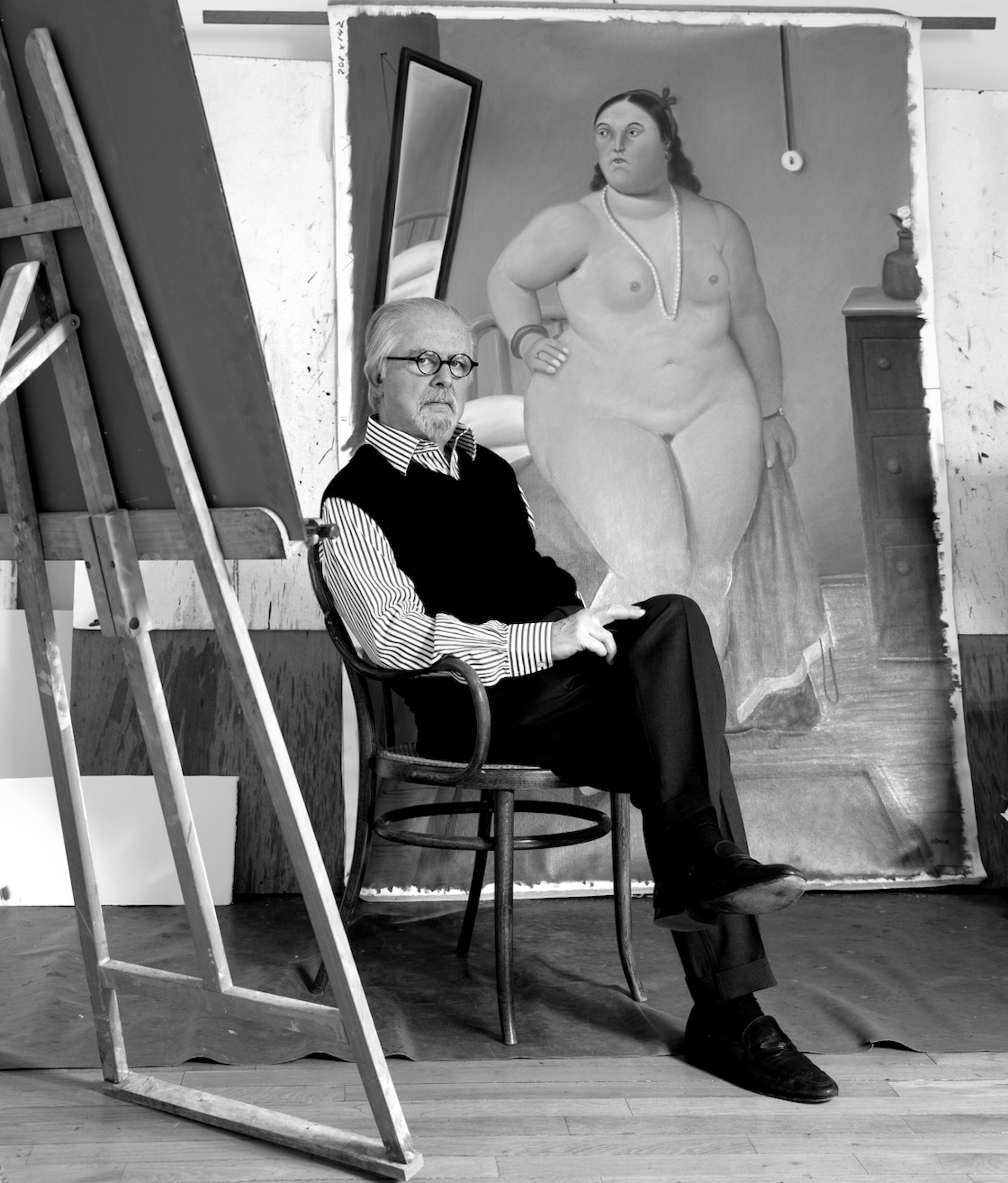 Fernando Botero in his studio in Paris, sat in front of a portrait of a woman