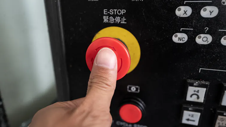 a person's thumb pressing a large red button