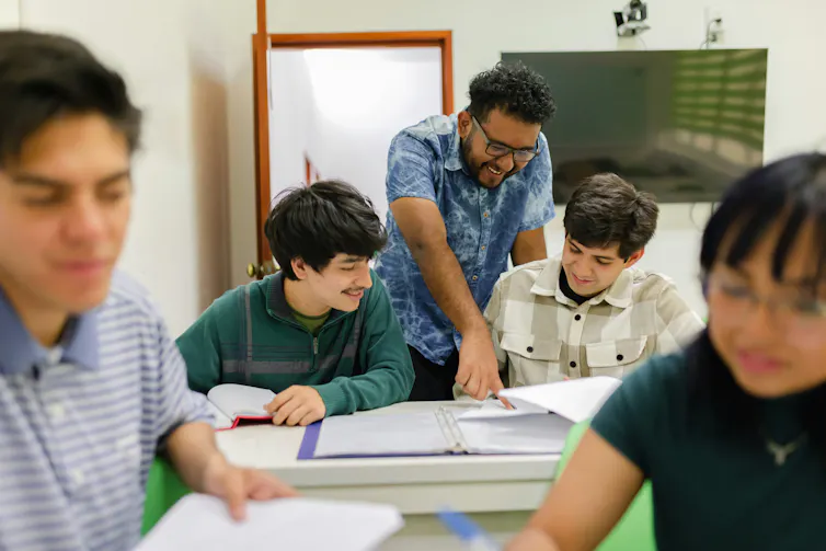 A teacher talking to students who seem to be smiling in a knowing and insightful way.