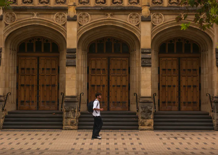 A photograph of a student walking in front of a university building.