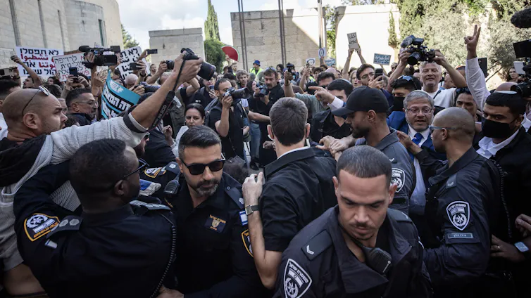 A group of people are seen with police in uniform at the front.
