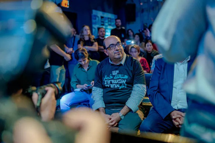 A man sits amid a group of people.