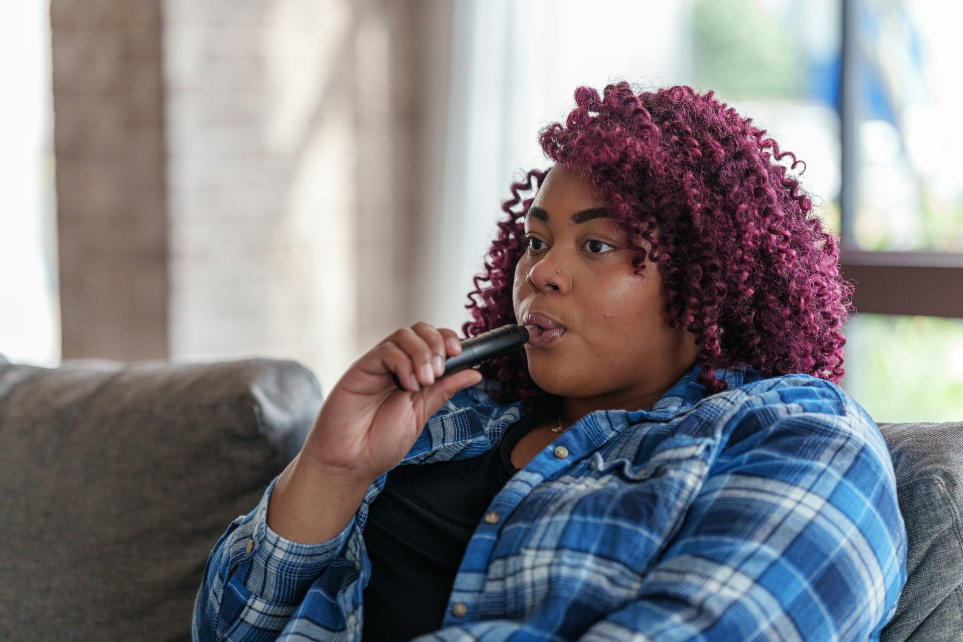 Woman sits on couch and vapes