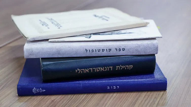 A stack of five books with white and blue covers and Hebrew words on the spines.